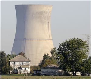The cooling tower of the Davis-Besse Nuclear Power Station looms over an adjacent farm.