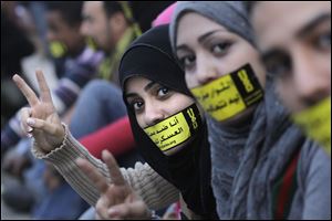 Egyptian activists tape their mouths shut with an Arabic slogan reading 