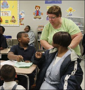 Horace Reynolds, Jr., asks teacher Nancy Young a question while his sister Shania Taylor, 2, foreground, and their mother, Maryann Taylor, attend 'Parent Power Hour' at Robinson Elementary. Inviting parents to the school once a month is one of the initiatives the school is taking in its effort to lift student performance.