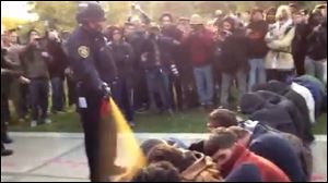 In this image made from video, a police officer uses pepper spray as he walks down a line of Occupy demonstrators sitting on the ground at the University of California, Davis on Friday.