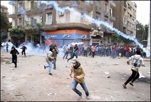 Protesters run from tear gas during clashes with Egyptian riot police in Tahrir Square in Cairo, Egypt, Sunday.