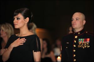 Sgt. Scott Moore, left, and his guest, actress Mila Kunis stand during the National Anthem at the 236th Marine Corps birthday ball for 3rd Battalion, 2nd Marine Regiment, 2nd Marine Division in Greenville, N.C.