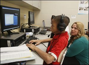 Robinson teacher Tamra Bacon observes seventh-grader Randy martin's progress as he reads on a computer.