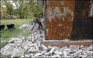 Chad Devereaux works at cleaning up the bricks that fell from three sides of his in-laws home in Sparks, Okla., Sunday, after two earthquakes hit the area in less than 24 hours.