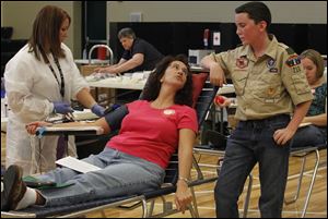 Red Cross nurse Amanda Larkins draws blood from Sara King during a pint size hero drive at Beverly Elementary in South Toledo. Ms. King’s son, John Metzger, a seventh grader at Beverly, kept his mother company at the event Monday.
