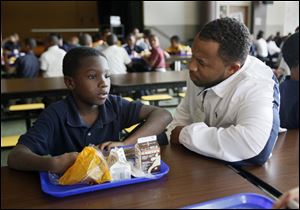 Marquan Whittaker, a third grader at Robinson Elementary, pauses in the school cafeteria to listen to the advice of Lawrence D. Tribble, Jr., a member of the Village 50 volunteers who help before and during school.