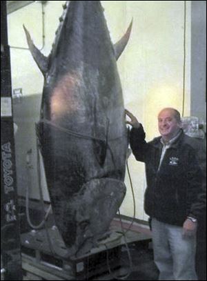 Fishing boat owner Carlos Rafael stands with an 881-pound tuna. The fish was snared as Rafael's crew set a net to catch bottom-dwelling fish. 