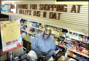 Alfred Dailey, owner of Dailey's Dis N Dat , sits behind the counter of his convenience store chatting with customers.