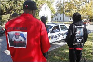 Toledo police officers speak to members of Lil Heads gathered near a memorial for Justin Smith, who was killed while attending a vigil for Deandre Green. The pictures on the members' coats are in honor of Justin Smith.