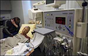 Randy Steele undergoes dialysis while his son, Jonathon, sits with him. Mr. Steele waited weeks to learn that his insurer would pay for an out-of-network, second evaluation to determine whether he was a candidate for a potentially life-saving kidney-liver transplant.