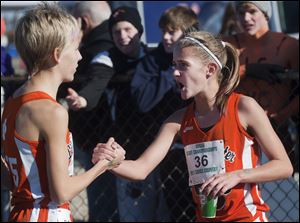 Brittany Atkinson, right, celebrates with Kelly Haubert after Atkinson won the Division III girls cross country race and the Tigers captured the team title.
