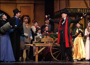 Paul Causman as Scrooge, front right, celebrates the joy of Christmas with his nephew, Fred, second from left, played by Zach Lahey, and townspeople. The Rep production features 130 actors and singers from northwest Ohio and southeast Michigan.