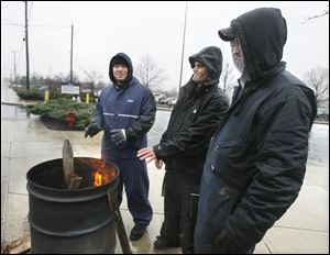 Locked-out Cooper Tire & Rubber workers, from left, Josh Smith, Don Brink, and Tim Haley try to stay warm outside the Findlay plant. Talks between the union and management continue.