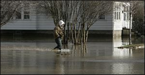 Phillip Kaczorowski sloshes through the flood water in front of his We. Monroe St. home in Dundee, Mich.