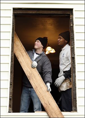 Maumee Valley Habitat for Humanity interns Kyle Hlebak, left, Andre Mack, right, remove a baseboard as they and volunteers from the Home Repair Ministry work on a home, Friday.