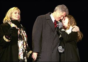 Chelsea Clinton gets a hug from her father, the President-elect Bill Clinton, during inaugural festivities in 1993, as her mother looks on.