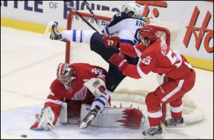 Winnipeg's Evander Kane (9) falls into the net between Detroit goalie Jimmy Howard and Niklas Kronwall.