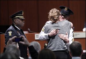 Tamee Hoover hugs her husband, Richard Hoover, after giving him his new lieutenant’s badge at the ceremony. Eight officers were honored; a ninth is to be promoted Friday.