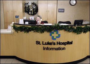 Barb Warner mans the information desk at St. Luke’s Hospital, where finances are improving and which is expected to be in the black this year.