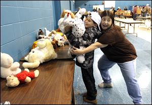 Ean Allgire, 8, of Toledo tries to hold as many stuffed animals as he can while volunteer Sandy Moore joins in the fun at the Christmas giveaway at Little Flower Catholic Church.