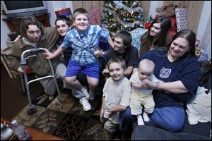 The Johnson family from left: Dad Jack, John, 11, Zachary, 9, Wrennie, 16, Jesse, 6, Ashley, 13, Rosey, 5 months, and mom Dew, in front of their Christmas presents and tree in their Locust St. home in Toledo.