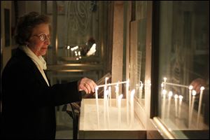 Barbara Hartford of Toledo lights a prayer candle Saturday, before a Christmas Eve service at Holy Trinity Greek Orthodox Cathedral in Toledo, Ohio.