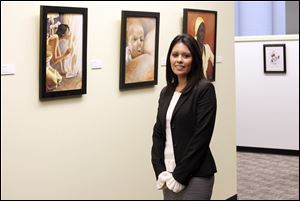 Diana Rodriguez stands in front of  artwork made a prisoner named Raymond Towler in The  Federal Public Defender's office.
