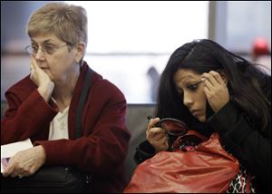 Travelers sit while they wait for their flight Friday at O'Hare International Airport in Chicago.