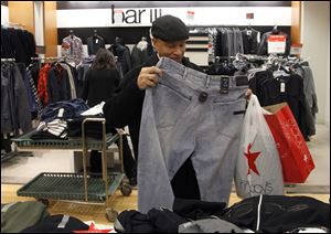 Jerry Clay shops at Macy’s on State Street in Chicago. A monthly survey finds consumers’ confidence in the economy surged to the highest level since April and is close to a post-recession peak. The component of the index reflecting the assessment of the job market improved in December.