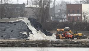 City of Toledo trucks load up with salt at the storage piles on Water Street, Tuesday.