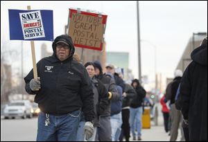 Ronnie L. Taylor, left, a 30-year maintenance worker, joins other postal workers Wednesday as they hold an informational picket in front of the Main Post office