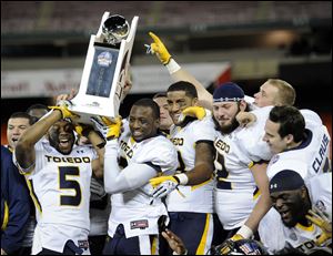 Toledo players including Diauntae Morrow (5) celebrate with the trophy after winning the Military Bowl against Air Force.