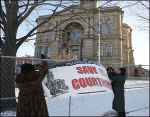 Lenora Livingston of Tiffin, left, and Brenda Stultz of northeastern Seneca County's Adams Township fasten a banner in front of the 1884 Beaux Arts-style  courthouse.