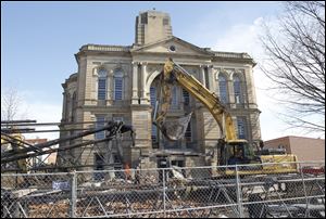 Workers prepare to assemble a crane, left, in preparation for demolition of The Seneca County Courthouse in Tiffin, Ohio.