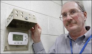Bill Pribe of Toledo Jet Center shows off one of the six digital thermostats installed in  the hangar at Toledo Express Airport as part of its efficiency upgrades.