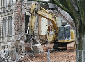 An excavator carries the cornerstone from the courthouse.