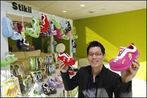 Stikii Shoes owner Joe Chew shows off his product, a line of shoes that children can decorate with color patches and emblems. Mr. Chew also owns Computer Discount, a chain of home computer stores.