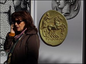 A woman speaks on her phone Friday in front of a Greek bank's adverting banner with ancient coins in Athens,.