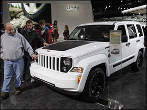 Howell, Mich. residents Pat Dowd, from left, and his sons Colin and Nolan, feel the hood of a Jeep Liberty during the North American International Auto Show in Detroit, Mich.