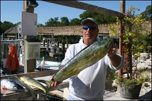 Bob Brown, Jr., holds a Dorado caught by a customer off the Florida Keys. Brown runs a wide, stout, 32-foot Century fishing boat. 