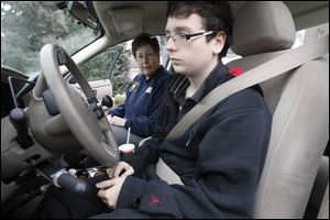 Paula Sanford, left, from Northwestern Ohio Driving School, and Zac Zies, 16, of Perrysburg, right, who suffers from an illness called Friedreich's ataxia, start their driving lesson. Zies uses special hand tools to drive.