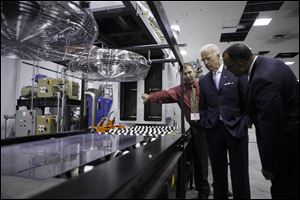 Mario Gatto, left, Engineering Manager, shows Vice-President Joe Biden, right, and Dir. of Recovery for Auto Communities and Workers Ed Montgomery, a semi conductor panel ready for processing during a tour of the Perrysburg startup Willard & Kelsey Solar Group.