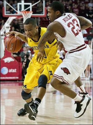Michigan's Trey Burke, left, drives against Arkansas' Julysses Nobles (23) in the final seconds of an NCAA college basketball game in Fayetteville, Ark., Saturday. Arkansas defeated Michigan 66-64.
