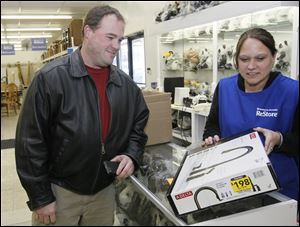 Tyler Young of Whitehouse, left, purchases a faucet from Britany Houghton of Toledo at Habitat for Humanity’s new ReStore on Conant Street in Maumee, in a former Carter Lumber warehouse.