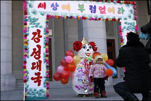 A North Korean man photographs a child in front of a New Year decoration as they celebrate the first day of the Lunar New Year in Pyongyang, North Korea.