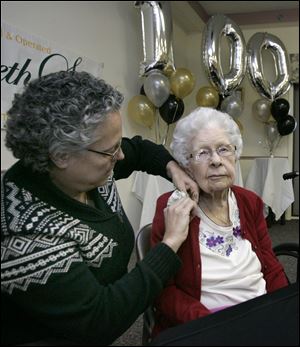 Waterville resident Patti Durivage pins a corsage on her aunt, Heloise Warrington, at the centenarians' birthday celebration.
