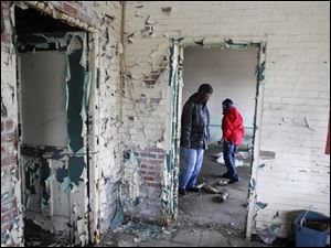 John Whitlow, left, and Lori Berry, outreach technicians with Neighborhood Properties, search for homeless people in a vacant building on Front Street in East Toledo.