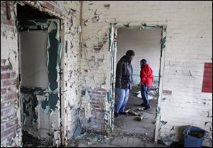John Whitlow, left, and Lori Berry, outreach technicians with Neighborhood Properties, search for homeless people in a vacant building on Front Street in East Toledo.
