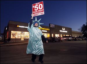 Isaac Underwood, a Statue of Liberty mascot for Liberty Tax Services on Monroe Street near Auburn Avenue, promotes the company’s services the day after the office was robbed. Although he has been a Liberty employee for three years, Thursday, the day of the holdup, was his first at the site.