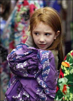 First grader Emma Sharpe tries on a Hawaiian outfit. 'Don't these clothes make you happy?' artist Meg Dickason asked students at Fairfield Elementary in Maumee. 
